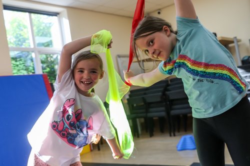 Plant yn chwifio rhuban lliwgar mewn dosbarth gymnasteg.