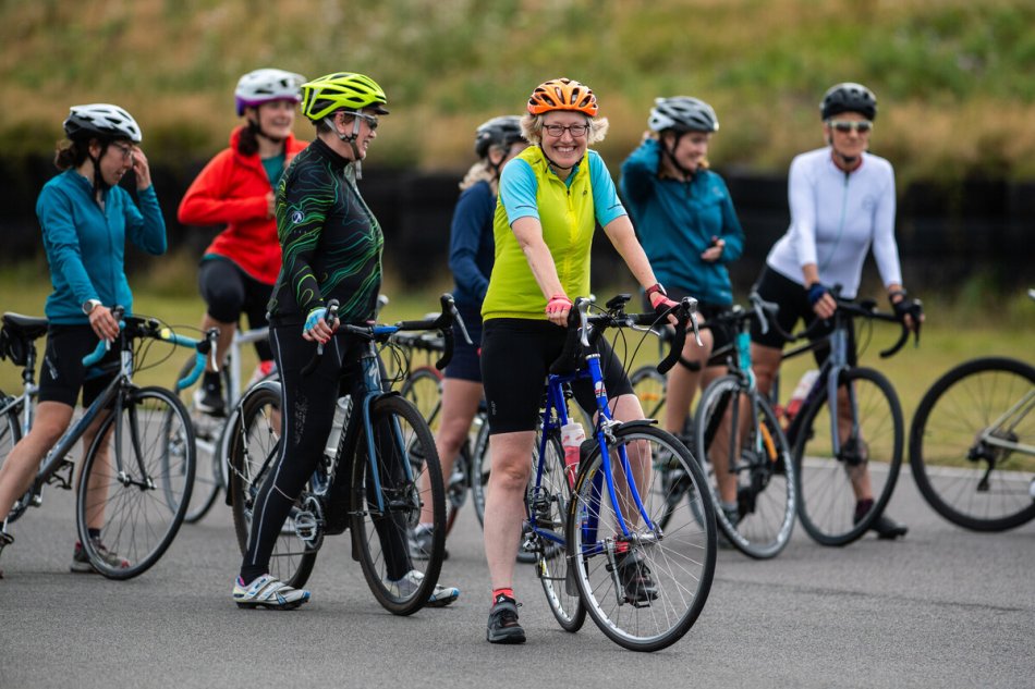 A woman on a bike smiles with a group of other women cyclists 