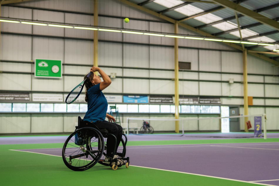 A woman in a wheelchair playing tennis.