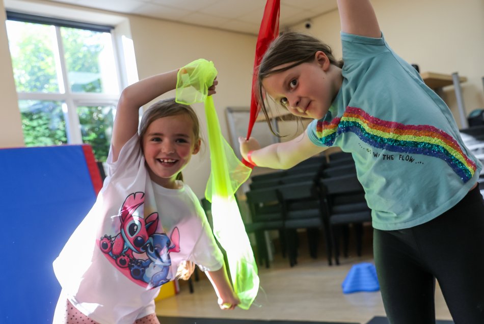 Plant yn chwifio rhuban lliwgar mewn dosbarth gymnasteg.